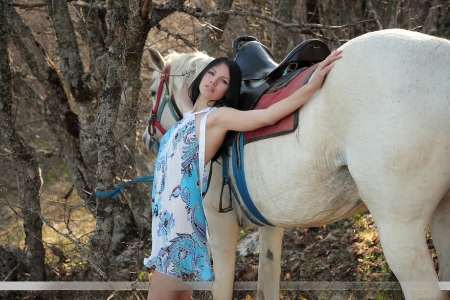 Dark haired teen Nichole A dismounts her horse in woods to pose totally naked