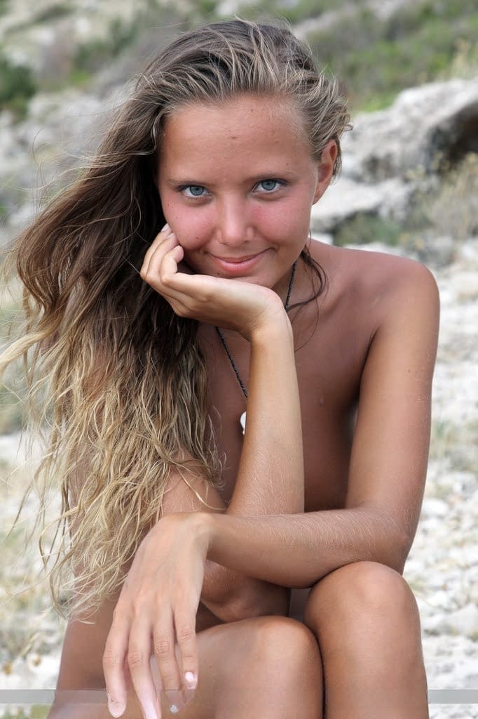 Solo girl Mango A modeling naked on rocky beach after disrobing