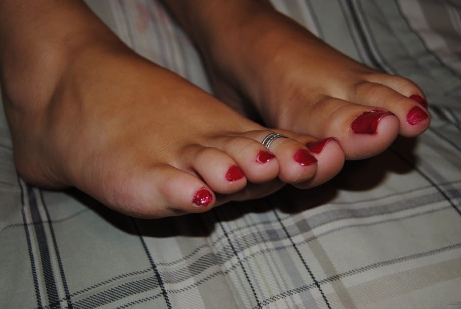 Brunette solo girl with painted toenails exposes her bare boobs