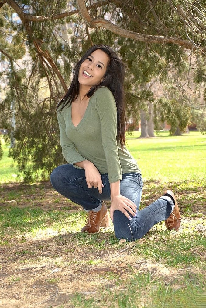 Latina chick Bella Quinn climbs a tree in the park wearing a sweater and jeans