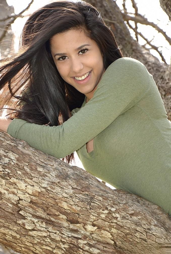 Latina chick Bella Quinn climbs a tree in the park wearing a sweater and jeans