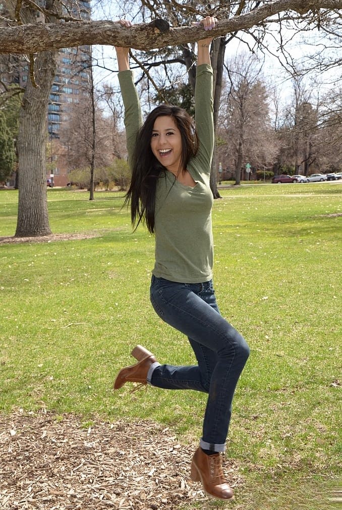 Latina chick Bella Quinn climbs a tree in the park wearing a sweater and jeans