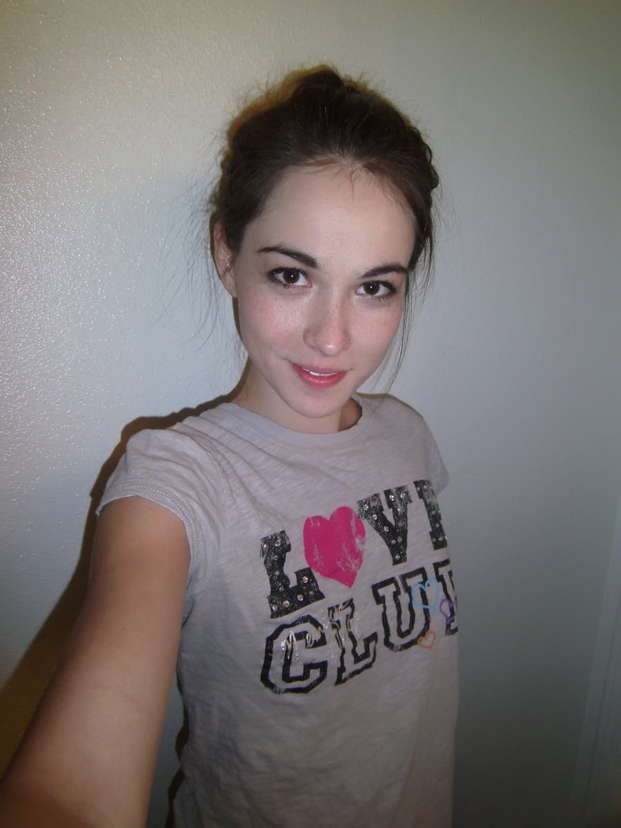 Cute brunette Emily undressing to take self shots of her bare tits and hot ass