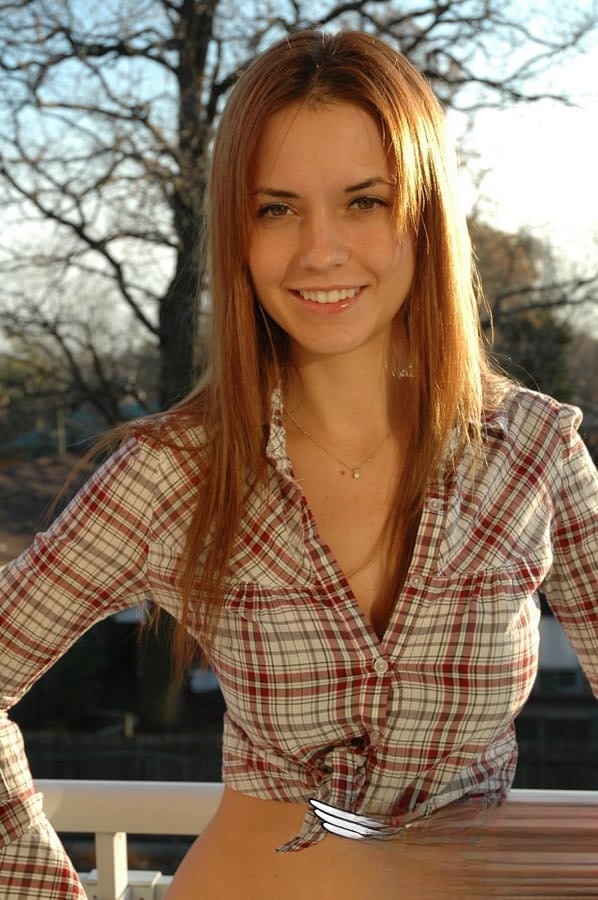Redheaded country girl models non nude in tied up shirt and denim jeans
