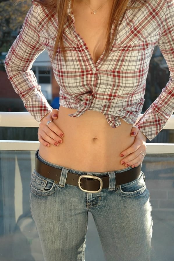 Redheaded country girl models non nude in tied up shirt and denim jeans