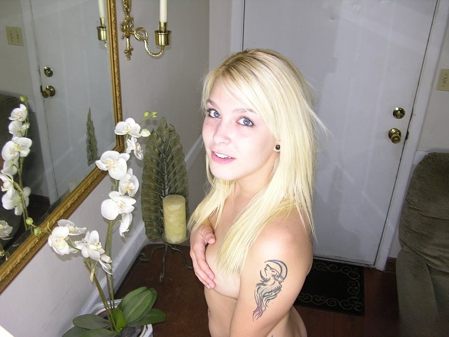 Young blonde strums on her electric guitar while modelling in the nude