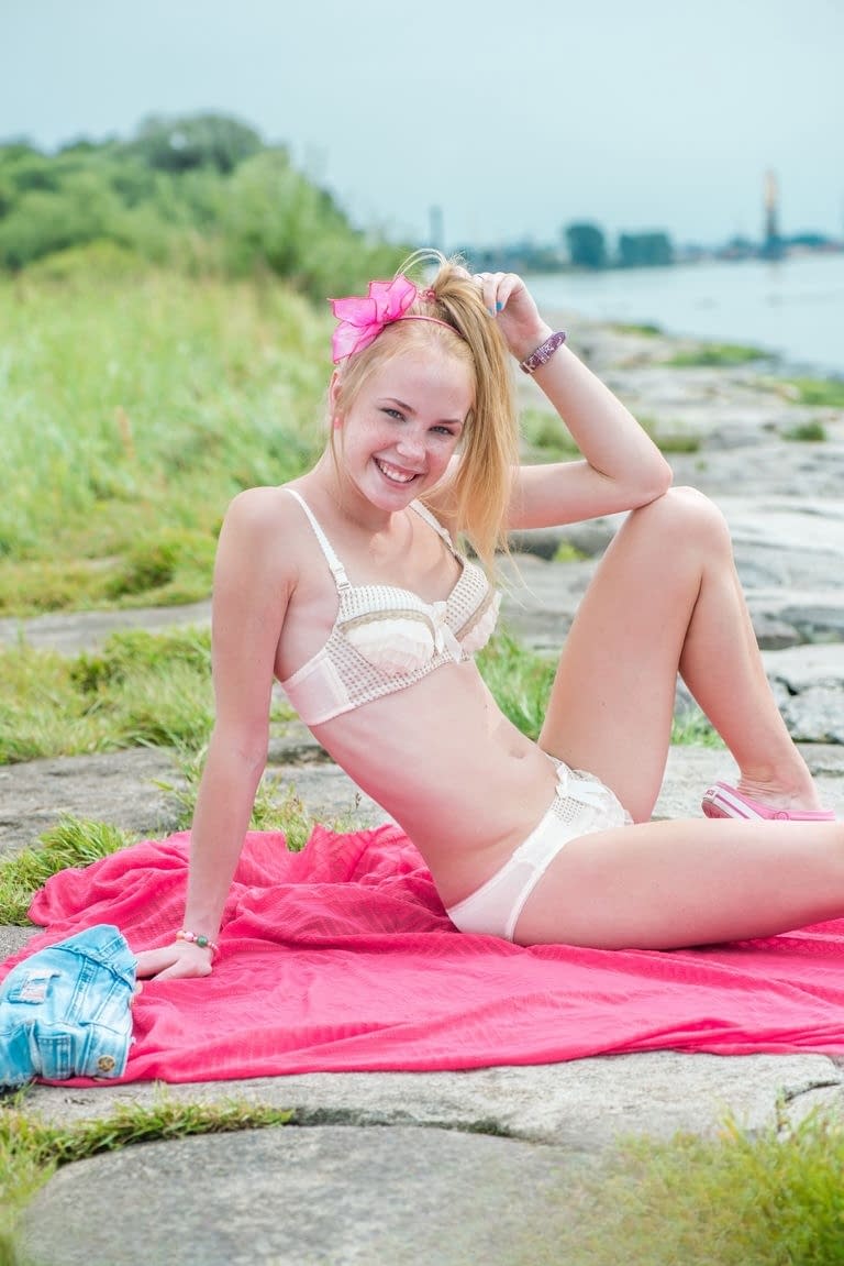 Blonde cutie Runa removes her shorts outdoors and gets on her knees naked