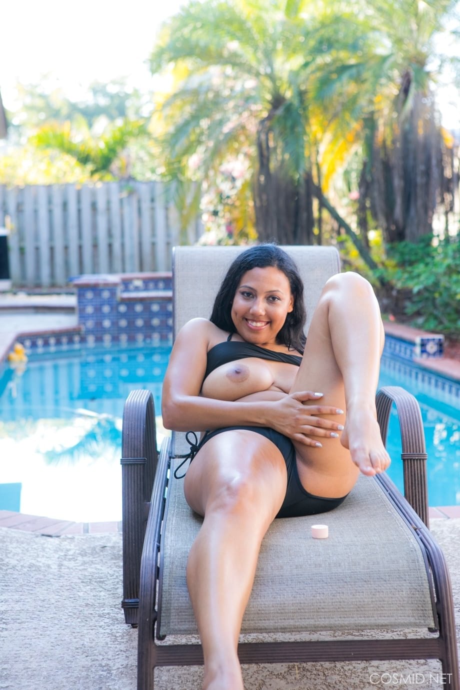 Chubby black amateur removes her bikini to pose nude on chair by a pool