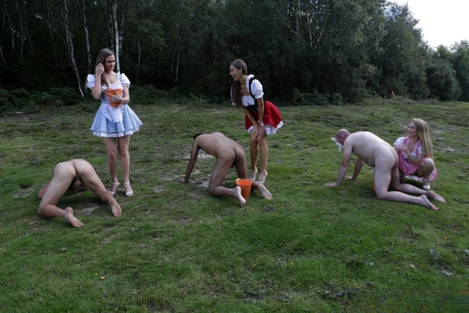 Horny femdom girls in costume head to the field to milk their naked man slave
