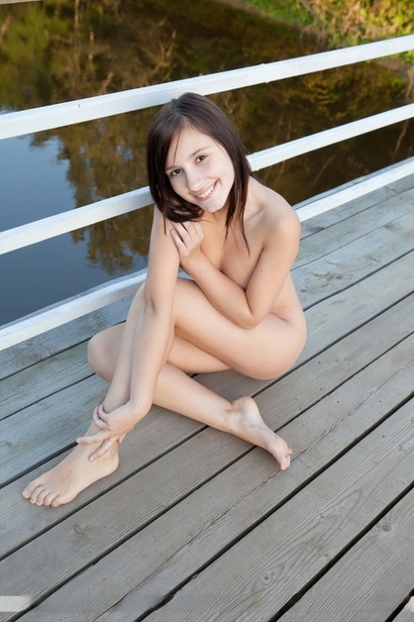 Brunette teen Rosalin E showcases her bald cunt on a footbridge