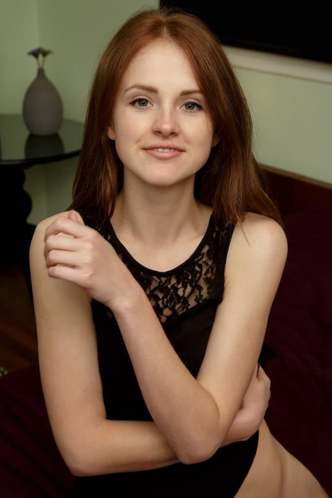 Young redhead Alice May shows off her bald cunt while removing stockings