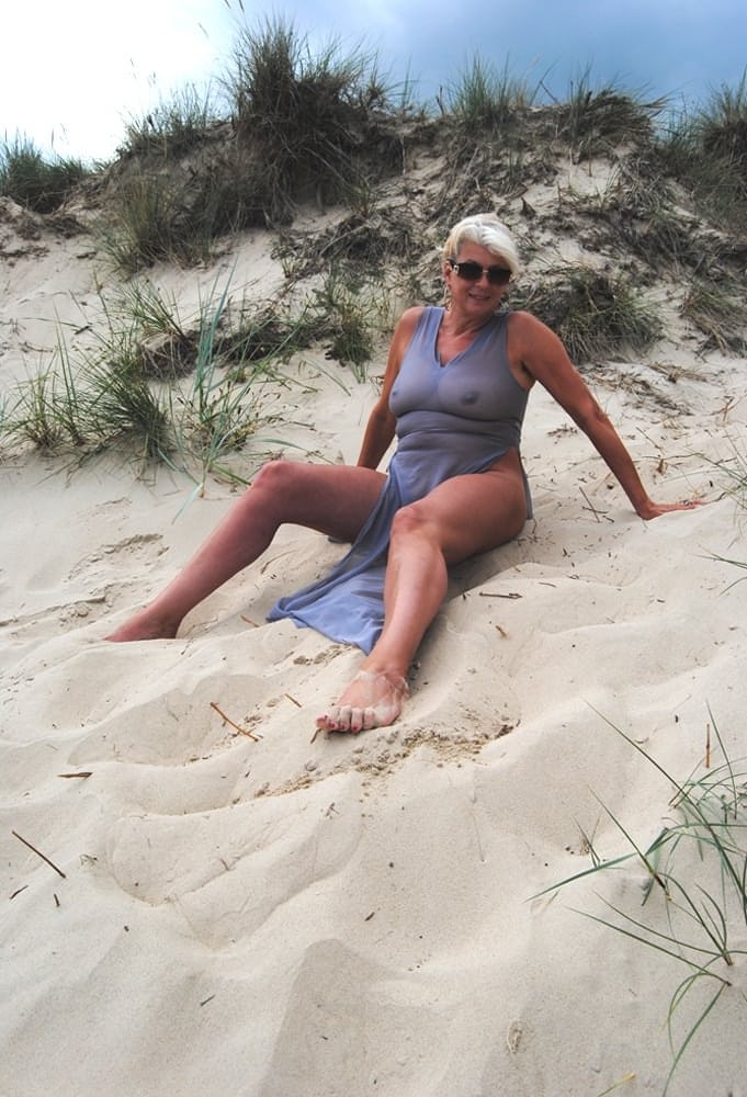 Beautiful busty mature Dimonty poses fully clothed in sheer dress at the beach