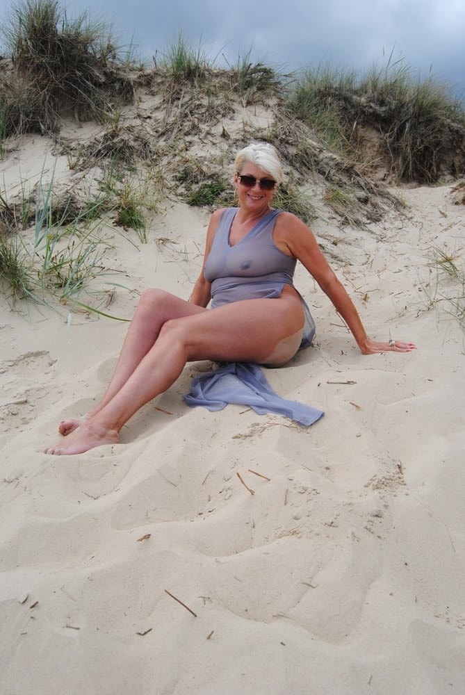 Beautiful busty mature Dimonty poses fully clothed in sheer dress at the beach