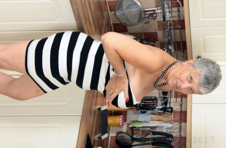 Old woman with short grey hair bares saggy tits as she strips naked