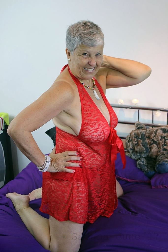 Mature granny Savana in red lingerie laughs as she poses all sexy on the bed