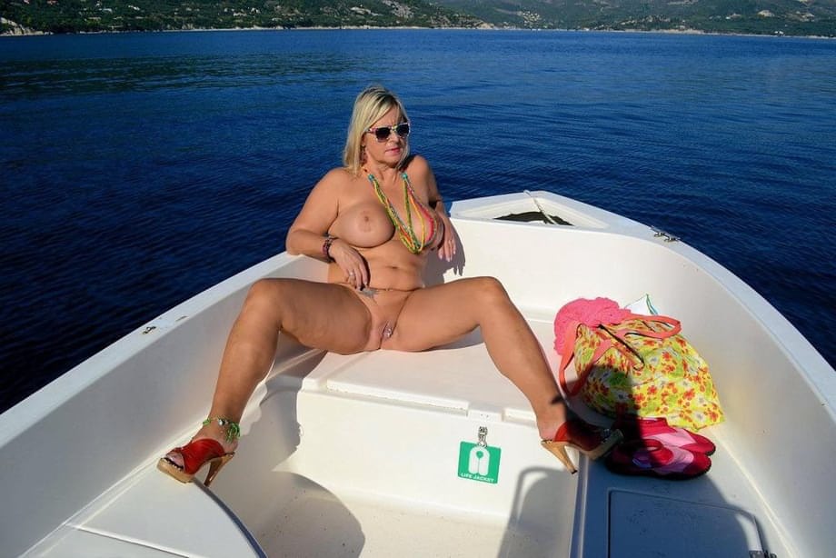Busty blonde Chrissy pilots her speed boat nude to sun her thick naked body