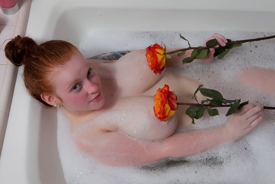 Pale redhead Kaycee Barnes displays her large boobs and butt during a bath