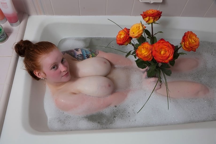 Pale redhead Kaycee Barnes displays her large boobs and butt during a bath