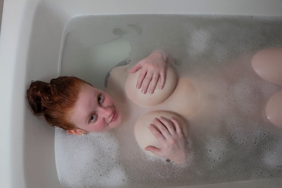 Pale redhead Kaycee Barnes displays her large boobs and butt during a bath