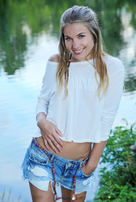 Adorable teen Lola Krit proudly shows her bald pussy by a pond