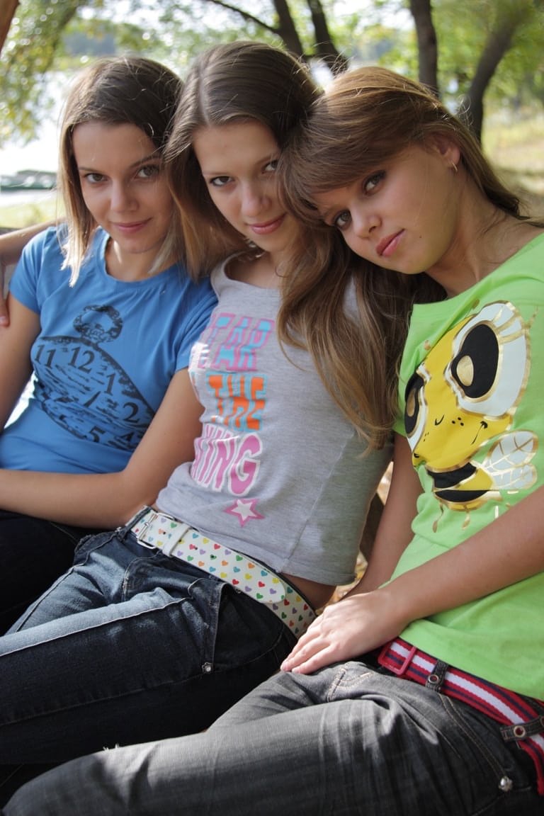 3 young girls remove T-shirts and jeans to model naked on park bench