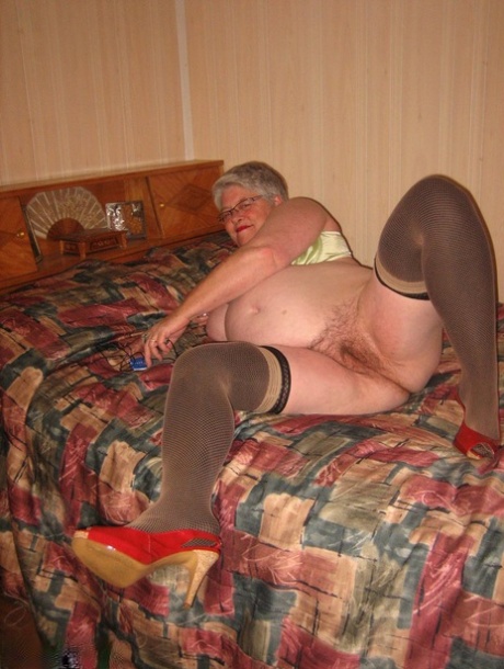 Fat granny Girdle Goddess pets her pussy after stripping to hosiery on her bed