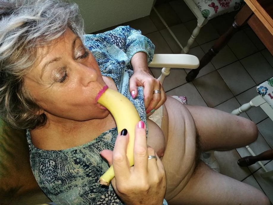Horny granny Caro sticks a banana inside her natural pussy on kitchen chair