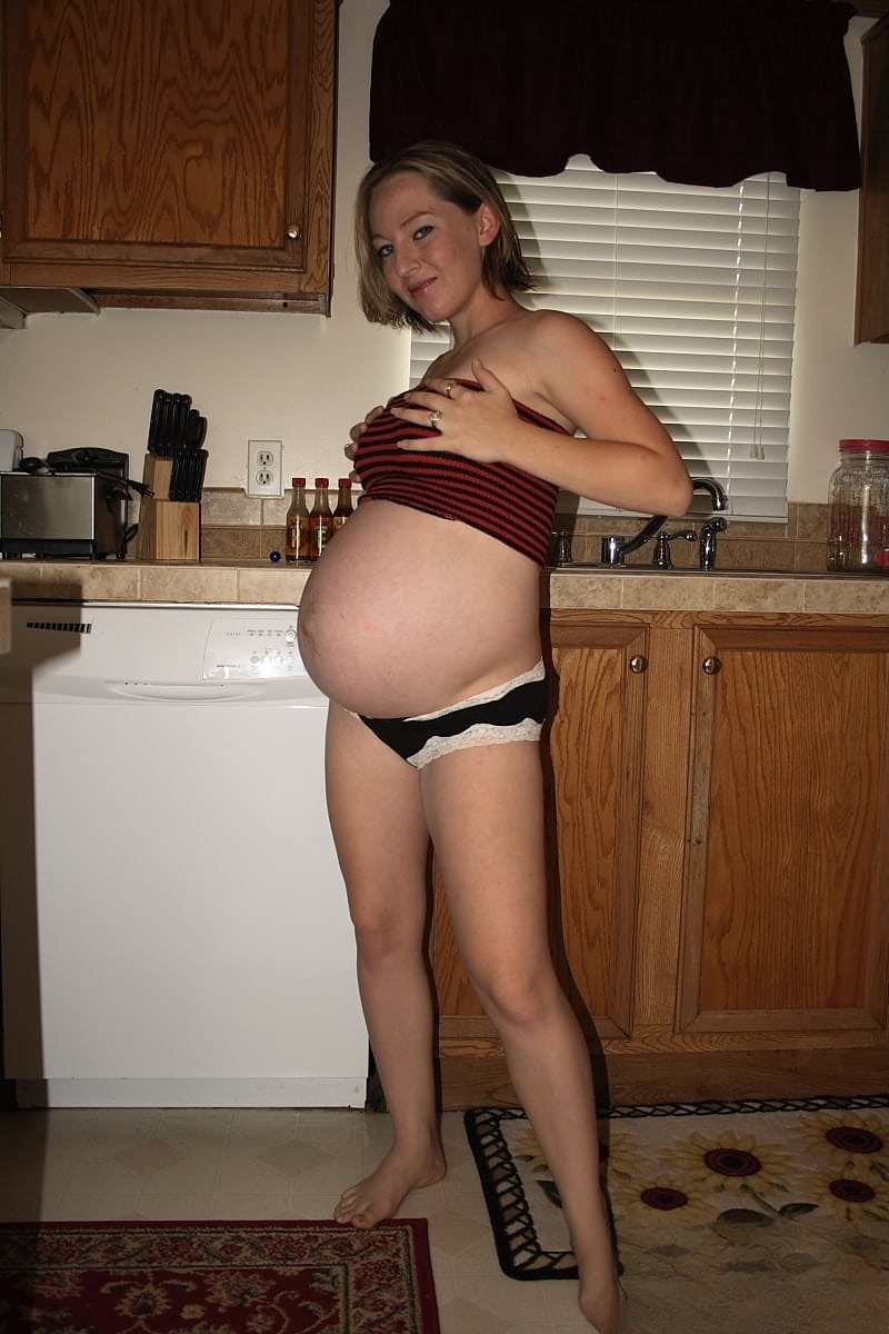 Pregnant amateur removes a tube top before slipping out of sexy panties