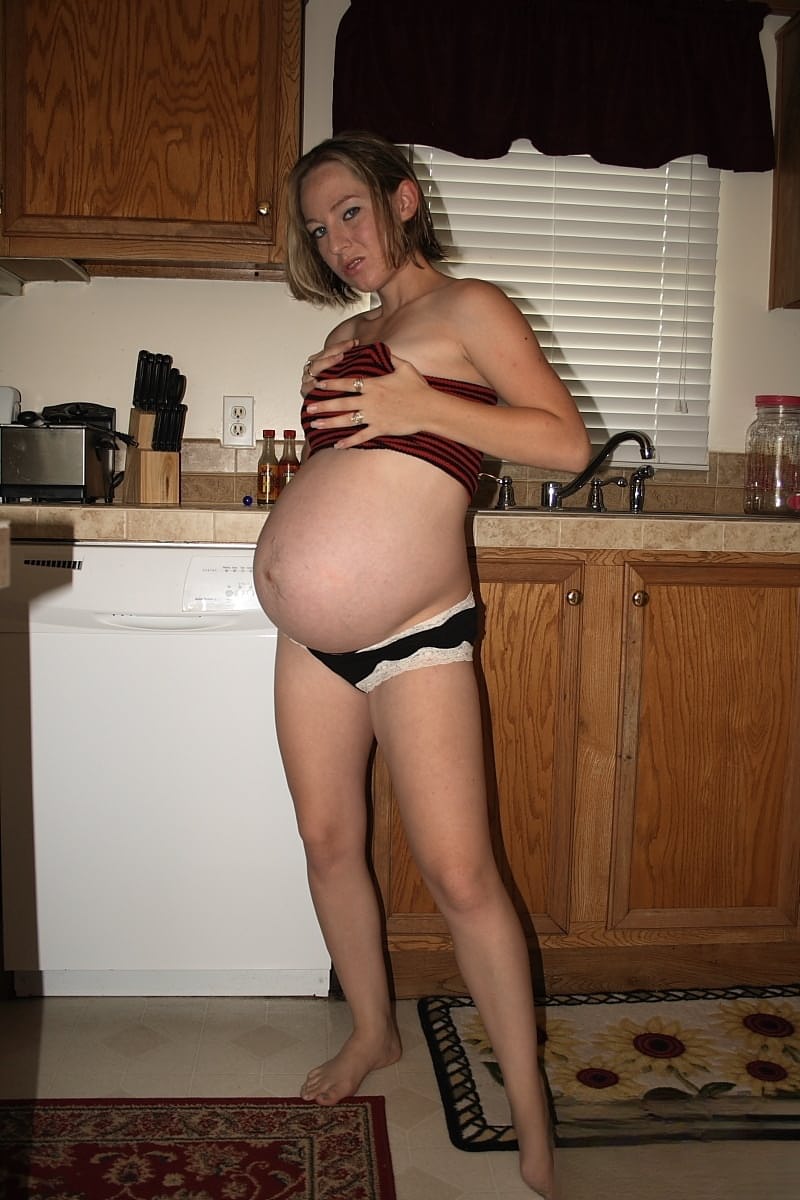 Pregnant amateur removes a tube top before slipping out of sexy panties