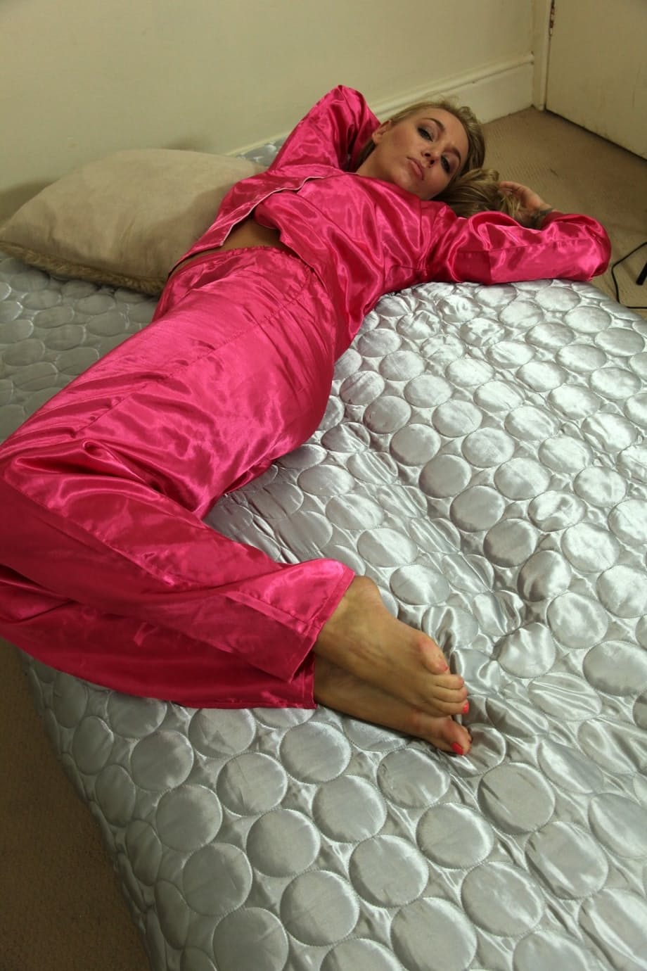Blonde girl Hayley Marie Coppin shows her bare feet wearing satin pajamas