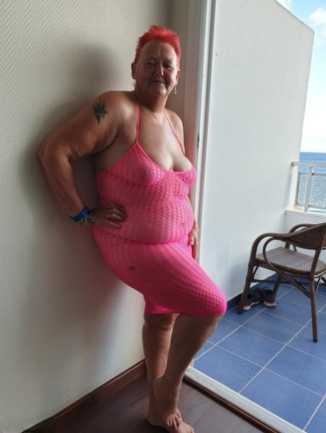 Fat nan with short red hair finger spreads her pussy on oceanside balcony
