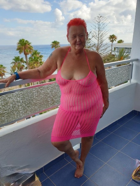 Fat nan with short red hair finger spreads her pussy on oceanside balcony