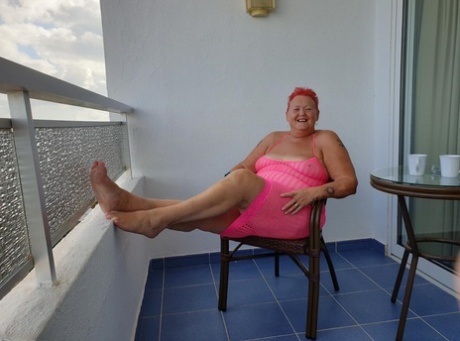 Fat nan with short red hair finger spreads her pussy on oceanside balcony