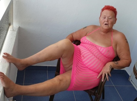 Fat nan with short red hair finger spreads her pussy on oceanside balcony