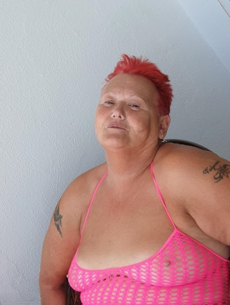 Fat nan with short red hair finger spreads her pussy on oceanside balcony