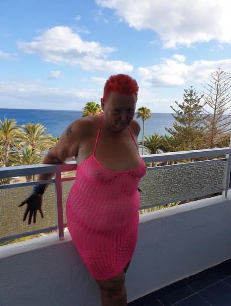Fat nan with short red hair finger spreads her pussy on oceanside balcony