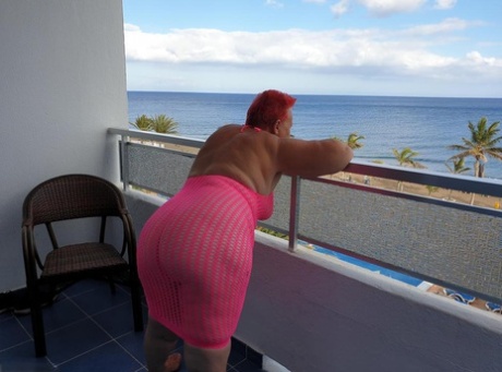 Fat nan with short red hair finger spreads her pussy on oceanside balcony