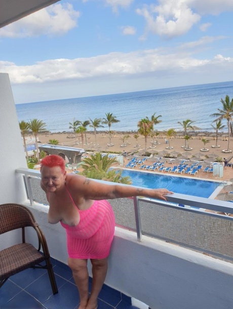 Fat nan with short red hair finger spreads her pussy on oceanside balcony