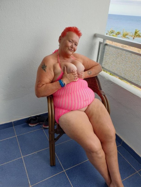 Fat nan with short red hair finger spreads her pussy on oceanside balcony