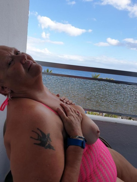 Fat nan with short red hair finger spreads her pussy on oceanside balcony