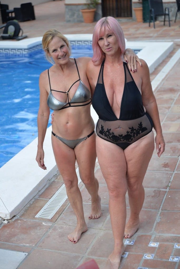 Mature amateurs share a lesbian kiss in their swimwear on poolside patio
