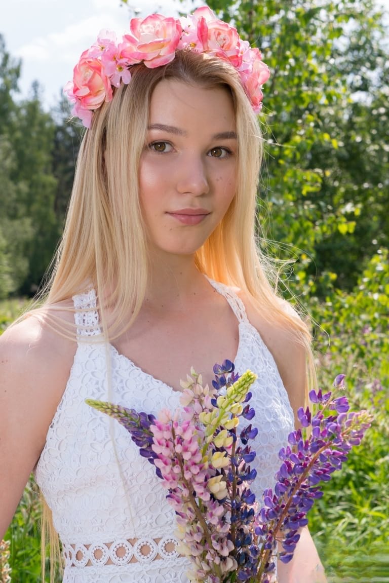 Young blonde wears a crown of flowers during her nude debut amid fireweed