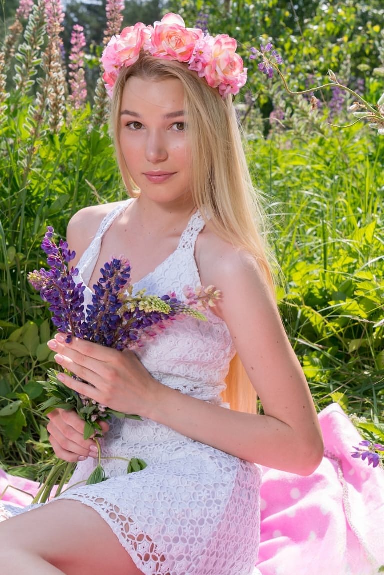 Young blonde wears a crown of flowers during her nude debut amid fireweed