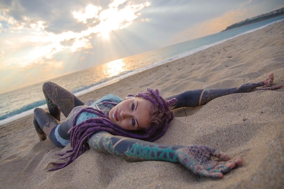 Heavily tattooed girl releases tiny tits from bikini top on a sandy beach