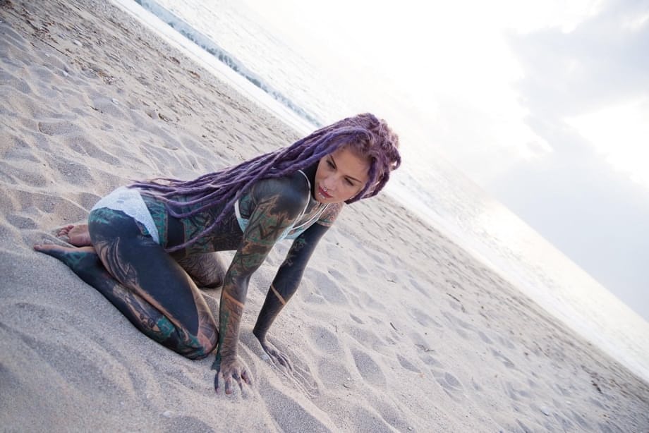 Heavily tattooed girl releases tiny tits from bikini top on a sandy beach