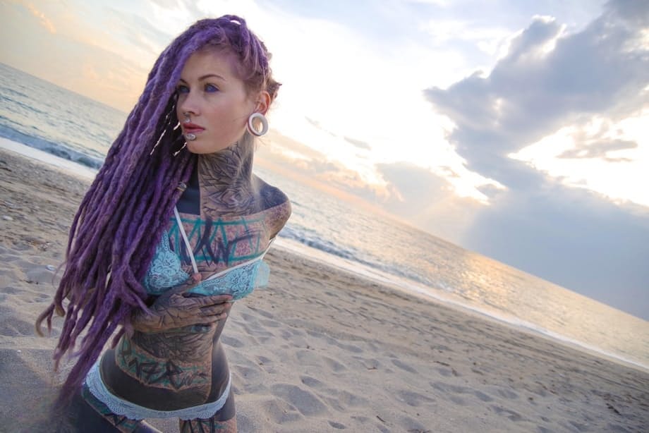 Heavily tattooed girl releases tiny tits from bikini top on a sandy beach