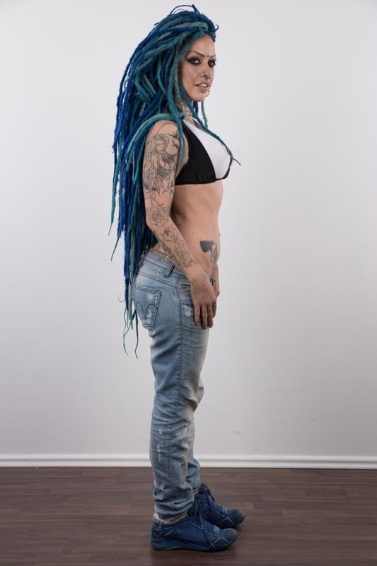 Punk girl with a headful of dyed dreads stands naked in her modelling debut