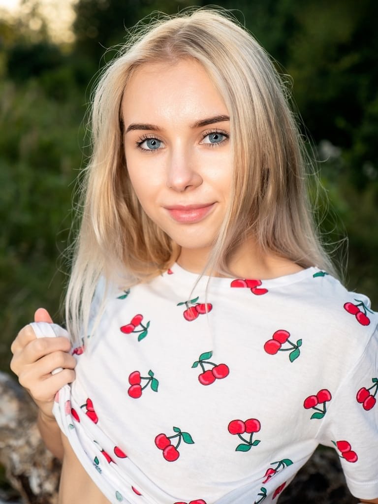 Teen first timer Maya finger spreads her pink twat on a felled tree in a field