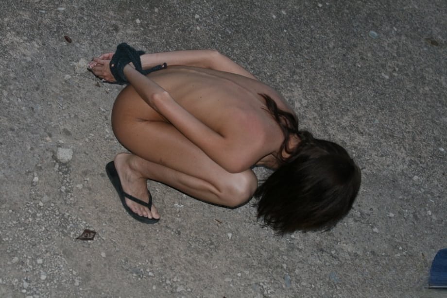 Naked slave girls are spanked and whipped by their handler outdoors
