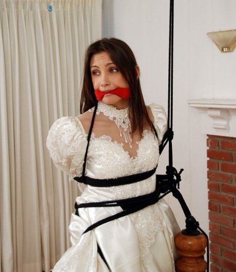 Brunette bride Celeste Star is ballgagged and tied up in her wedding dress